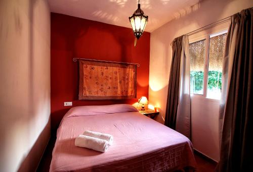 Habitación pequeña de color rojo con cama y ventana en Casas el Camino, en Zahora