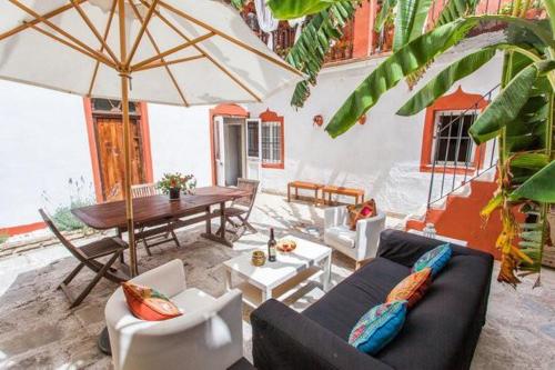 ein Wohnzimmer mit Sofas und einem Tisch mit einem Sonnenschirm in der Unterkunft Apartamentos El Patio Andaluz in Jerez de la Frontera