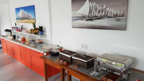 a kitchen with a counter with red cabinets and a painting at Pousada Caminho da Praia in Jericoacoara