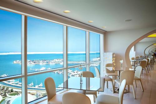 a restaurant with tables and chairs and a view of the ocean at The Art Hotel & Resort in Manama
