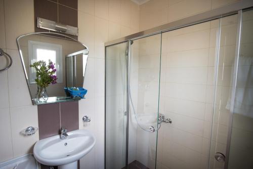 a bathroom with a shower and a sink and a mirror at Baywatch Hotel in Chrani