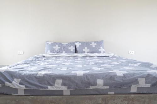 a bed with a blue and white comforter and pillows at TF Apartment in Chiang Mai