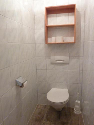 a white bathroom with a toilet and a shelf at Appartement-Pension Familie Gewessler in Bad Mitterndorf