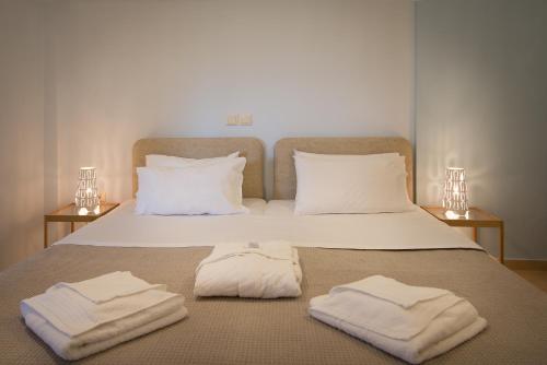 a bed with white towels on it with two lamps at Baywatch Hotel in Chrani