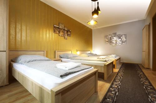 two beds in a room with yellow walls at Fehér Hattyú Panzió in Orosháza