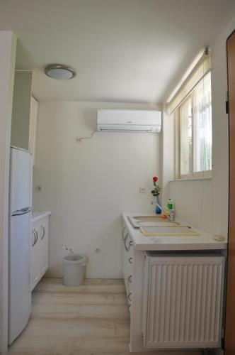 a white kitchen with a sink and a refrigerator at Cosy Studio with Garden / Individual apartment in Athens