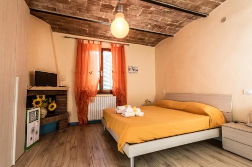 カスティリオーネ・デル・ラーゴにあるResidenza il Casoneのベッドルーム1室(オレンジのシーツが入ったベッド1台、窓付)
