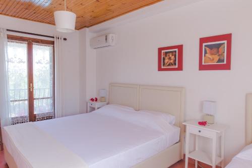 ein weißes Schlafzimmer mit einem großen Bett und 2 Tischen in der Unterkunft Villa Lola in Lithakia