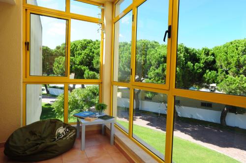 a room with large windows and a table with a book at Caparica Sun Centre in Costa da Caparica