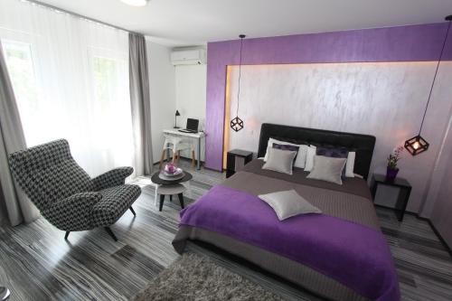 Dormitorio púrpura con cama y silla en New Belgrade Apartment ARENA en Belgrado