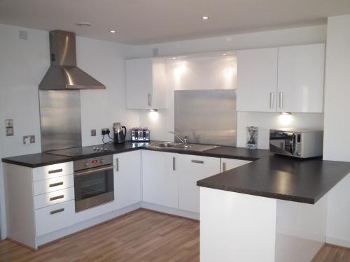 a kitchen with white cabinets and a black counter top at Edinburgh Western Harbour in Edinburgh