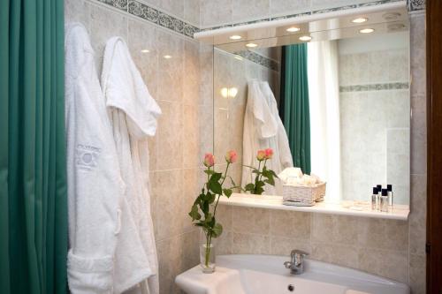 ein Bad mit einem Waschbecken und einem Spiegel in der Unterkunft Royal Olympic Hotel in Pinzolo