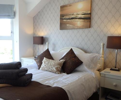 um quarto com uma cama branca com almofadas em Saint Cadfans Lodge em Tywyn