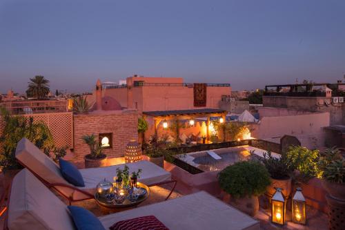 un patio en la azotea con mesas y sillas y una piscina en Dar Attajmil, en Marrakech