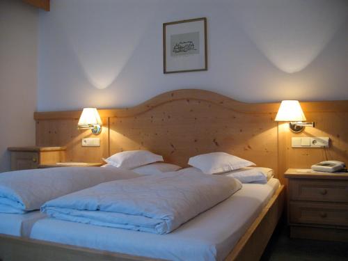 a bedroom with a large bed with two lamps at Pensione Sellablick in Colfosco