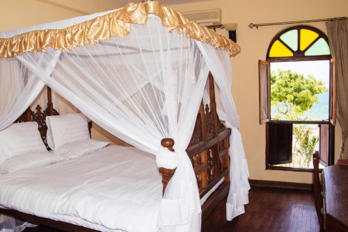 a bedroom with a canopy bed and two windows at Abuso Inn in Zanzibar City