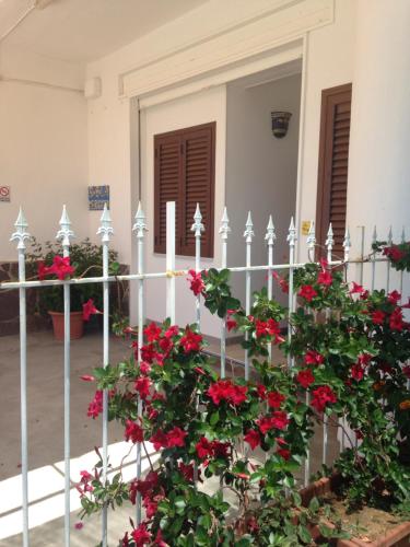 a white fence with red flowers in front of a house at La Meriggia B&B in Pisciotta