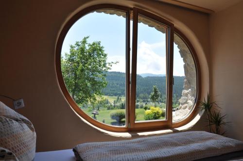 a bedroom with a large circular window with a view at Himmelsbögen und Apartments mit Seeblick und Alleinlage in Weissensee