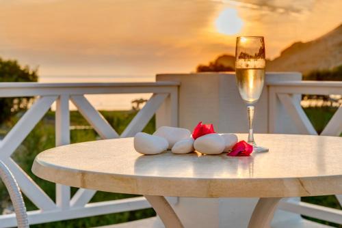 a white table with a glass of wine and some flowers at Hotel Benois in Galissas