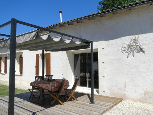 a patio with a table and chairs under a canopy at Le gite du gueurlet in Boresse-et-Martron