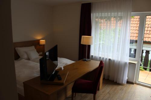 a bedroom with a bed and a desk with a television at Gasthof und Pension zum Löwen in Hirschberg an der Bergstraße