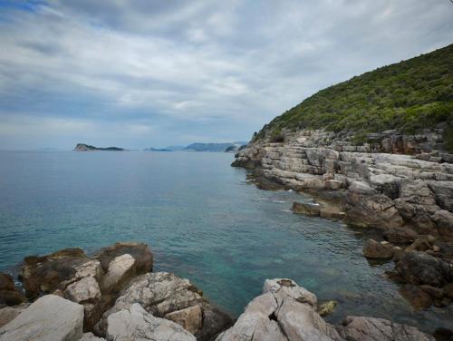 a large body of water next to a rocky shore at Apartments Močići in Močići