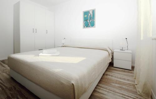 a white bedroom with a large bed and a table at Apartments Močići in Močići