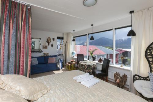 1 dormitorio con cama, mesa y ventana grande en Blómasetrið Homestay, en Borgarnes