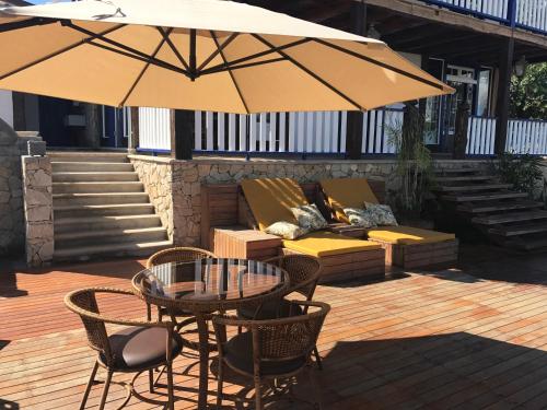 a patio with a table and chairs and an umbrella at Pousada Chão de Minas Ouro Preto in Ouro Preto