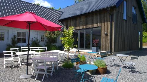 a patio with tables and chairs and a red umbrella at Elisetorp in Kivik