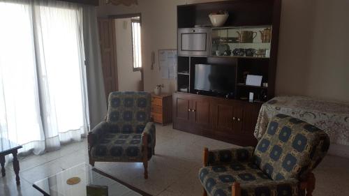 a living room with a tv and a chair and a table at Chariandry Court in Pissouri