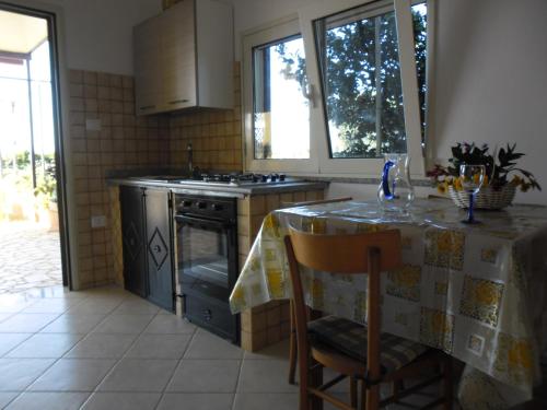 una cucina con tavolo e piano cottura forno superiore di Villetta Gelsomino a Corsano