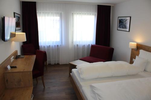 a hotel room with a bed and a desk and a chair at Gasthof und Pension zum Löwen in Hirschberg an der Bergstraße