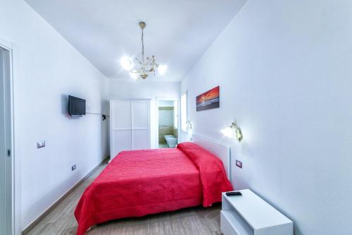 a white bedroom with a red bed with a red blanket at Isola Antica in SantʼAntìoco