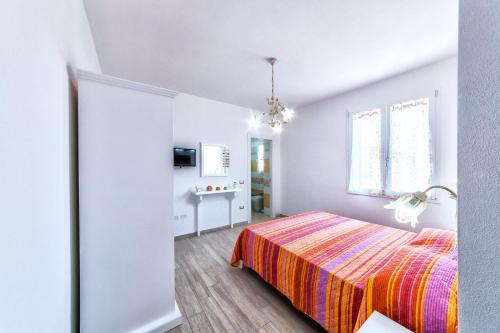 a white bedroom with a bed and a window at Isola Antica in SantʼAntìoco