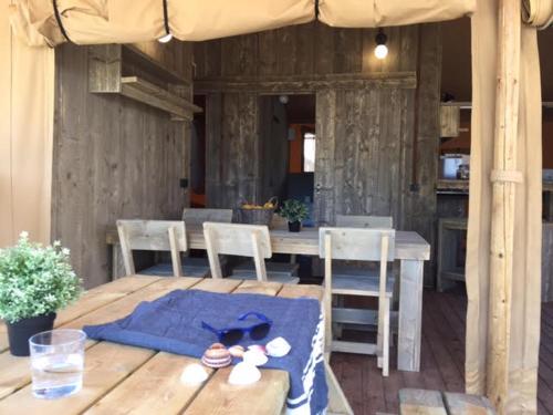 a wooden table with chairs and a table with an umbrella at Camping Sènia Caballo de Mar in Pineda de Mar