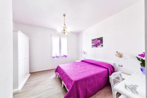 a white bedroom with a pink bed and a table at Isola Antica in SantʼAntìoco