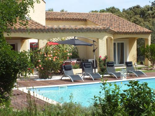 a house with a swimming pool with chairs and an umbrella at B&B Le Mas Des Chenes in Vacquières
