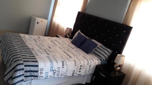 a bedroom with a bed with a black headboard and blue pillows at Jessma Bed and Breakfast in Walvis Bay