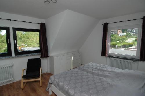 Ferienwohnung Sonneneck في Scharzfeld: غرفة نوم بسرير وكرسي ونوافذ اثنين