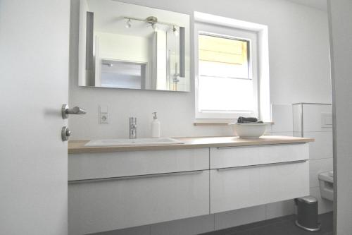 biała łazienka z umywalką i oknem w obiekcie Gästehaus Verl w mieście Verl
