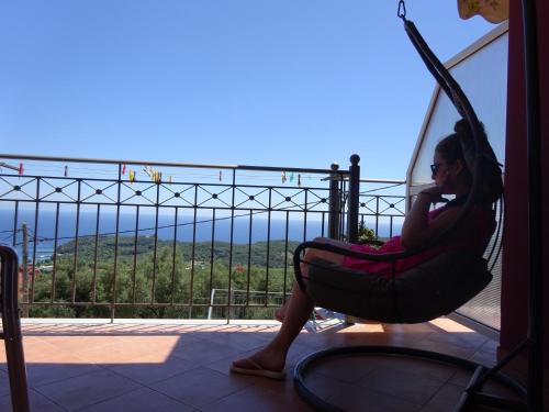 a woman sitting in a hammock on a balcony at Elena Rista Studios in Parga