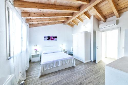 サンタンティーオコにあるイゾラ アンティカの白いベッドと木製の天井が備わるベッドルーム1室が備わります。