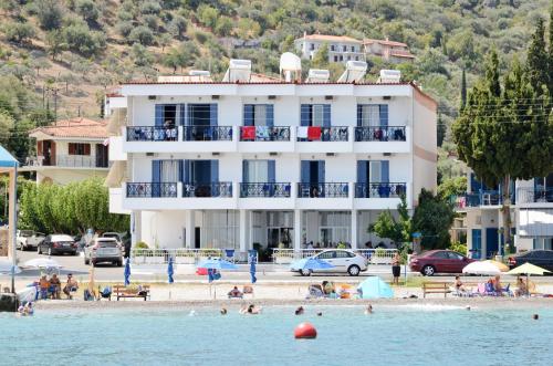 a building on a beach with people in the water at Hotel Blue Sea in Tiros