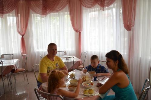 a group of people sitting at a table eating food at Hotel Venetsia in Sukko