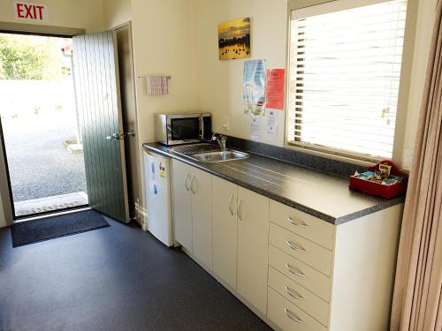 a small kitchen with a sink and a microwave at Tairua Shores Motel in Tairua