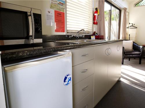 a kitchen with a sink and a microwave at Tairua Shores Motel in Tairua