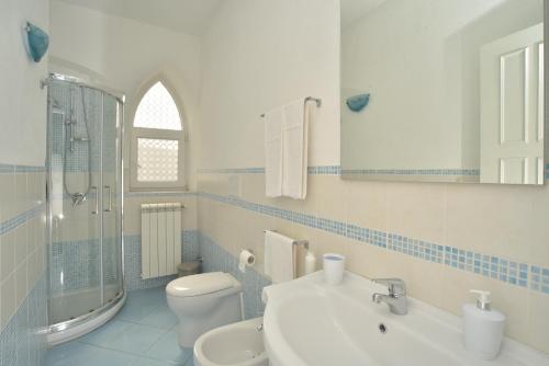 a white bathroom with a sink and a toilet at Villa al Porto in Ischia