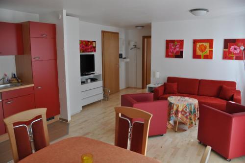 a living room with a red couch and a kitchen at Apart Hotel Stadtgarten in Überlingen