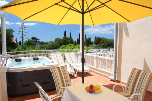 a yellow umbrella on a patio with chairs and a table at Apartments & Rooms Čakelić in Mlini
